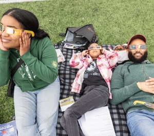 students out on the grass with eclipse glasses on